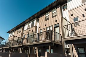 Okotoks apartment for rent - A row of townhouses with balconies and black railings.