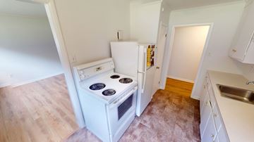 Fredericton apartment for rent - A white fridge and stove in a kitchen with wooden floors.