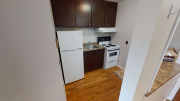 Fredericton apartment for rent - A kitchen with a white refrigerator and a stove top oven.