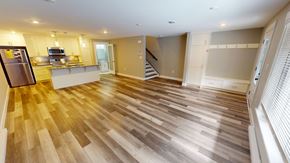 Fredericton apartment for rent - A spacious kitchen with wooden flooring and a refrigerator on the left.