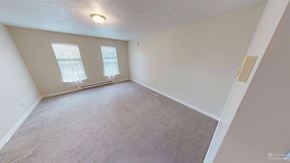 Fredericton apartment for rent - A spacious room with carpeted floor and two windows.