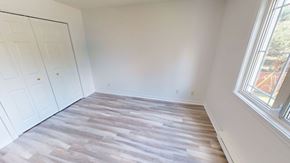 Fredericton apartment for rent - A room with a wooden floor and a window showing trees outside.