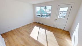 Fredericton apartment for rent - A room with a white door and a window with a view of a green building.
