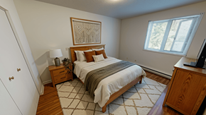 Fredericton apartment for rent - A bedroom with a bed, nightstand, and a painting on the wall.