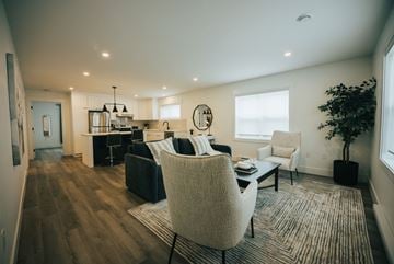 Fredericton apartment for rent - A modern living room with a black couch and a white chair.