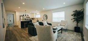 Fredericton apartment for rent - A modern living room with a kitchen area in the background.