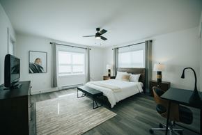 Fredericton apartment for rent - A bedroom with a bed, desk, and television.