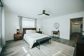 Fredericton apartment for rent - A bedroom with a bed, a chair, and a ceiling fan.