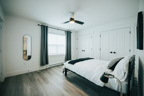 Fredericton apartment for rent - A bedroom with a bed, a ceiling fan, and a window with curtains.