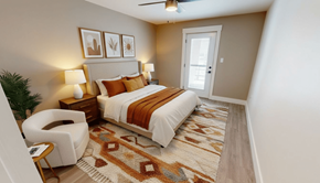 Fredericton apartment for rent - A bedroom with a bed, chair, and a rug.