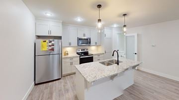 Fredericton apartment for rent - A modern kitchen with a stainless steel refrigerator, microwave, and sink.