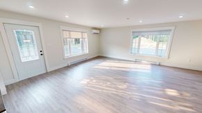 Fredericton apartment for rent - A spacious room with wooden floors and white walls.