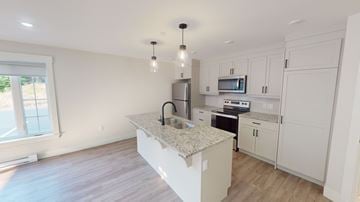 Fredericton apartment for rent - A kitchen with white cabinets and a granite countertop.