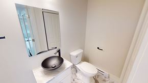 Fredericton apartment for rent - A bathroom with a toilet, sink and mirror.