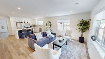 Fredericton apartment for rent - A modern living room with a grey sofa and a white chair.