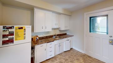 Fredericton apartment for rent - A kitchen with white cabinets and a white fridge.