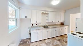 Fredericton apartment for rent - A kitchen with white cabinets and a marble countertop.