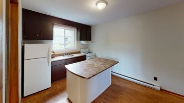 Fredericton apartment for rent - A kitchen with a white refrigerator and wooden cabinets.