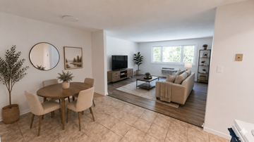 Fredericton apartment for rent - A living room with a round table and chairs, a television, and a rug.