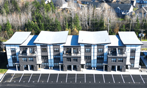 Fredericton apartment for rent - A parking lot in front of a building with grey and white exterior.