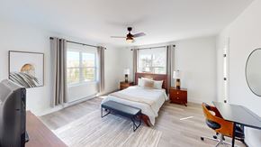 Fredericton apartment for rent - A bedroom with a bed, a chair, and a ceiling fan.