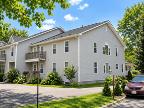 Fredericton apartment for rent - A white two-story apartment building with a red car parked in front.