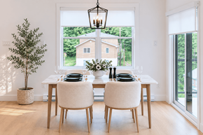 Fredericton apartment for rent - A dining room with a table set for two and a view of a house through the window.
