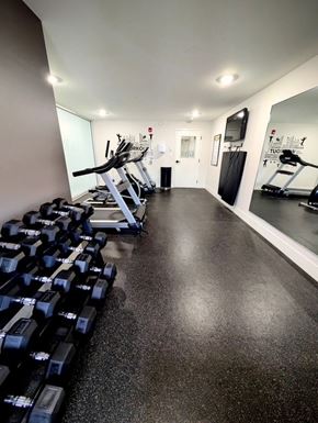 Fredericton apartment for rent - A gym with a row of dumbbells on the left and a mirror on the right.