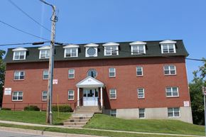 Fredericton apartment for rent - A red brick building with a white door and windows.