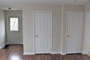 Fredericton apartment for rent - Three white doors in a room with wood floors and a window.