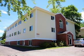 Fredericton apartment for rent - A white and red building with a car parked in front.