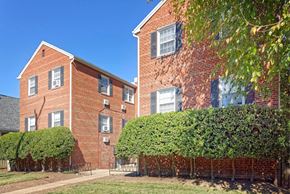 Alexandria apartment for rent - A red brick building with green bushes in front.