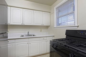 Alexandria apartment for rent - A kitchen with white cabinets and a black stove top oven.