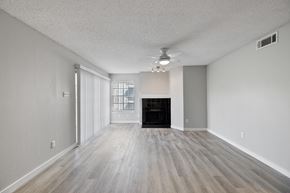 Dallas apartment for rent - A spacious room with a fireplace and wood flooring.