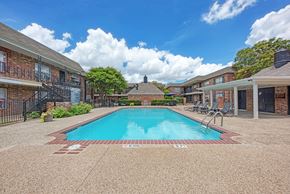 Austin apartment for rent - A swimming pool surrounded by a brick building and trees.
