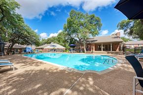 Austin apartment for rent - A pool surrounded by trees and a house.