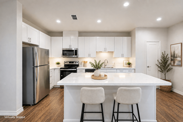 Austin apartment for rent - A kitchen with white cabinets and a white island with two chairs.