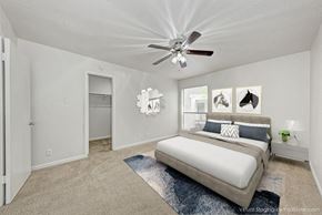 Austin apartment for rent - A bedroom with a bed, a ceiling fan, and pictures on the wall.