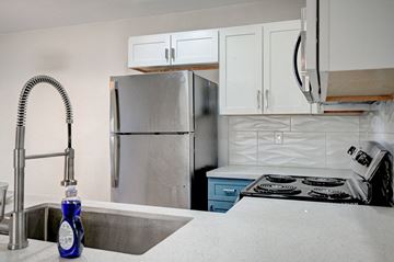 Las Vegas apartment for rent - A kitchen with a stainless steel refrigerator, a sink with a blue bottle on it, and a stove with a white top.