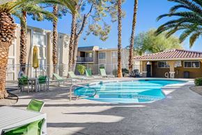 Las Vegas apartment for rent - A pool surrounded by palm trees and chairs.