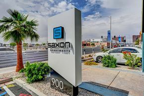 Las Vegas apartment for rent - A sign for Saxon Apartments stands in front of a street with a palm tree.