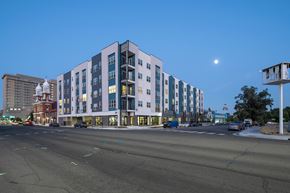 Reno apartment for rent - A modern multi-story building with a parking lot in front.