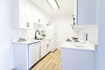 Las Vegas apartment for rent - A white kitchen with wooden floors and white cabinets.