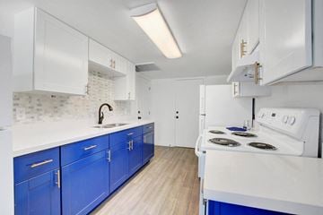 Las Vegas apartment for rent - A kitchen with blue cabinets and a white stove top oven.