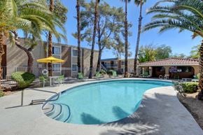 Las Vegas apartment for rent - A pool surrounded by palm trees and a yellow umbrella.