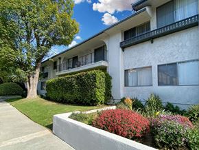Encino apartment for rent - A white building with a balcony and a green tree.