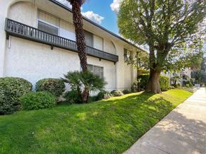 Encino apartment for rent - A white building with a balcony and a tree in front of it.