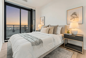 Hamilton apartment for rent - A bedroom with a large bed and a view of the city at dusk.