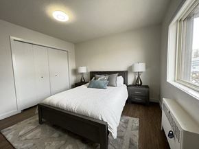 Calgary apartment for rent - A bedroom with a bed, nightstand, and a window.
