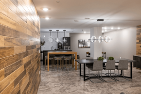 Edmonton apartment for rent - A modern dining room with a wooden wall on the left and a black table with grey chairs.